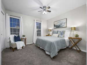 Bedroom featuring dark colored carpet, a ceiling fan, and a closet