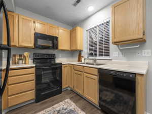 Kitchen featuring black appliances, light countertops, light wood finish cabinets, and a textured ceiling