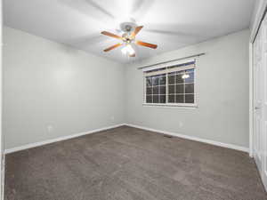 Unfurnished room with dark carpet, a textured ceiling, and ceiling fan
