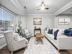 Living room with ornamental molding, wood finished floors, ceiling fan, and a textured ceiling