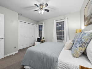 Bedroom featuring a ceiling fan, dark colored carpet, a closet, and a textured ceiling