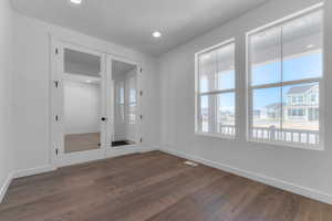 Unfurnished room featuring dark wood-style flooring, recessed lighting, and french doors