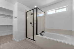 Bathroom featuring a stall shower, a walk in closet, a garden tub, and light tile patterned floors