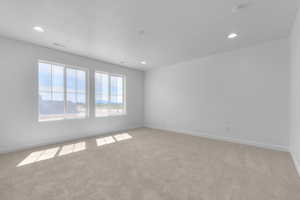 Empty room featuring light colored carpet, recessed lighting, and a smoke detector