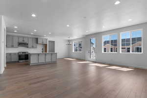 Kitchen featuring gray cabinetry, hanging lights, stainless steel appliances, open floor plan, and light countertops