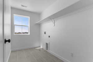 Laundry area featuring washer hookup, electric dryer hookup, and light tile patterned floors