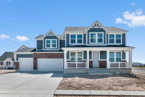 Craftsman inspired home with board and batten siding, driveway, covered porch, brick siding, and roof with shingles