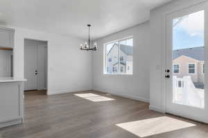 Unfurnished dining area featuring suspended lighting and dark wood finished floors