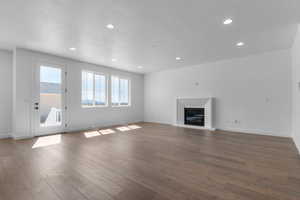 Unfurnished living room with a glass covered fireplace, a textured ceiling, dark wood-style flooring, and recessed lighting