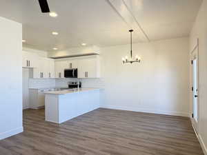 Kitchen featuring white cabinetry, a peninsula, tasteful backsplash, stainless steel appliances, and dark wood finished floors