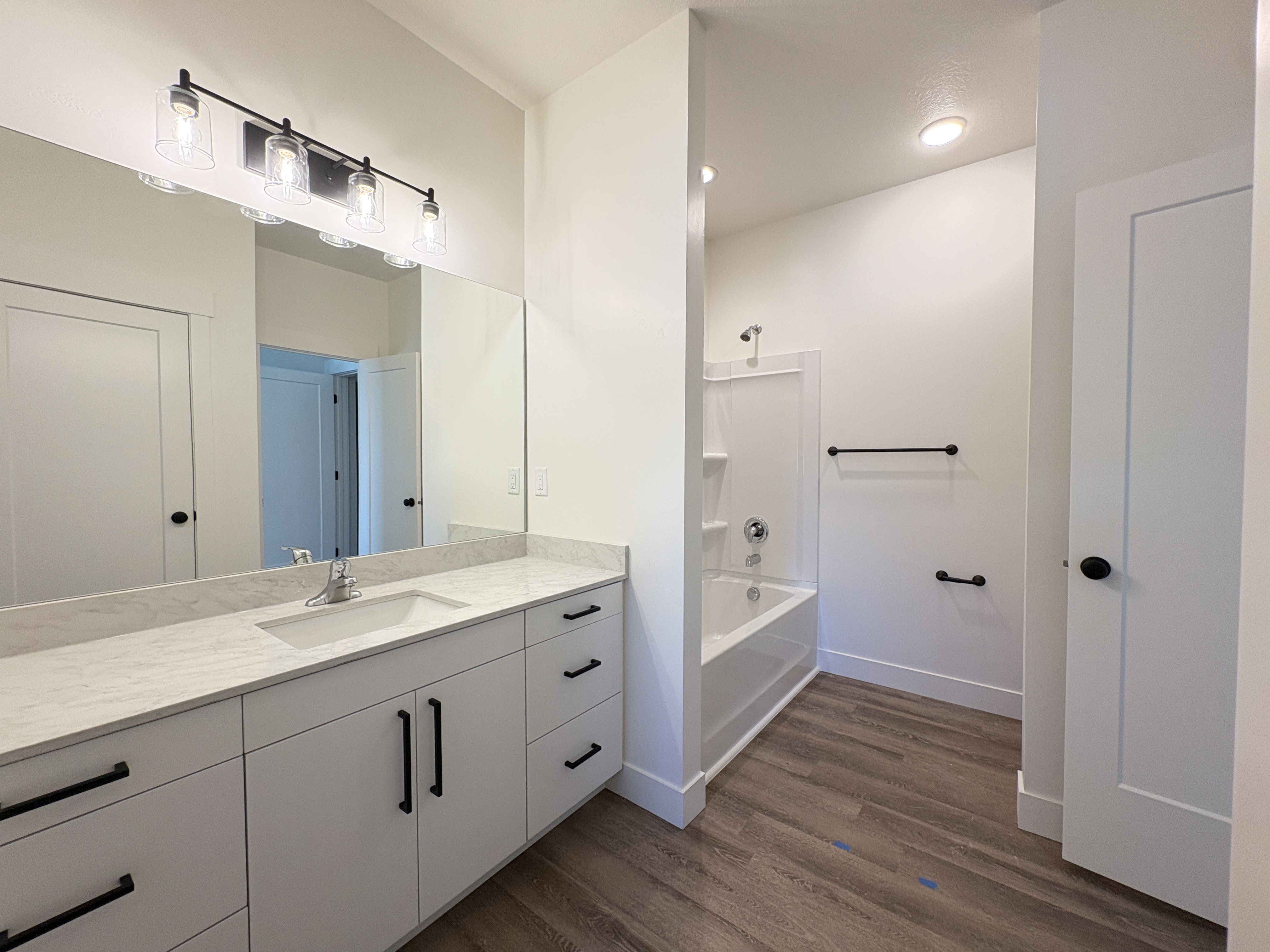 Full bathroom with vanity, dark wood-style floors, and shower / bathtub combination