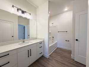 Full bathroom with vanity, dark wood-style floors, and shower / bathtub combination