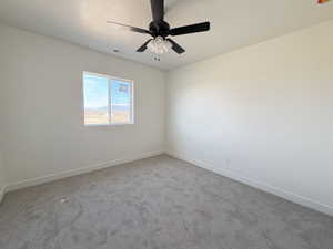 Carpeted empty room featuring baseboards and ceiling fan