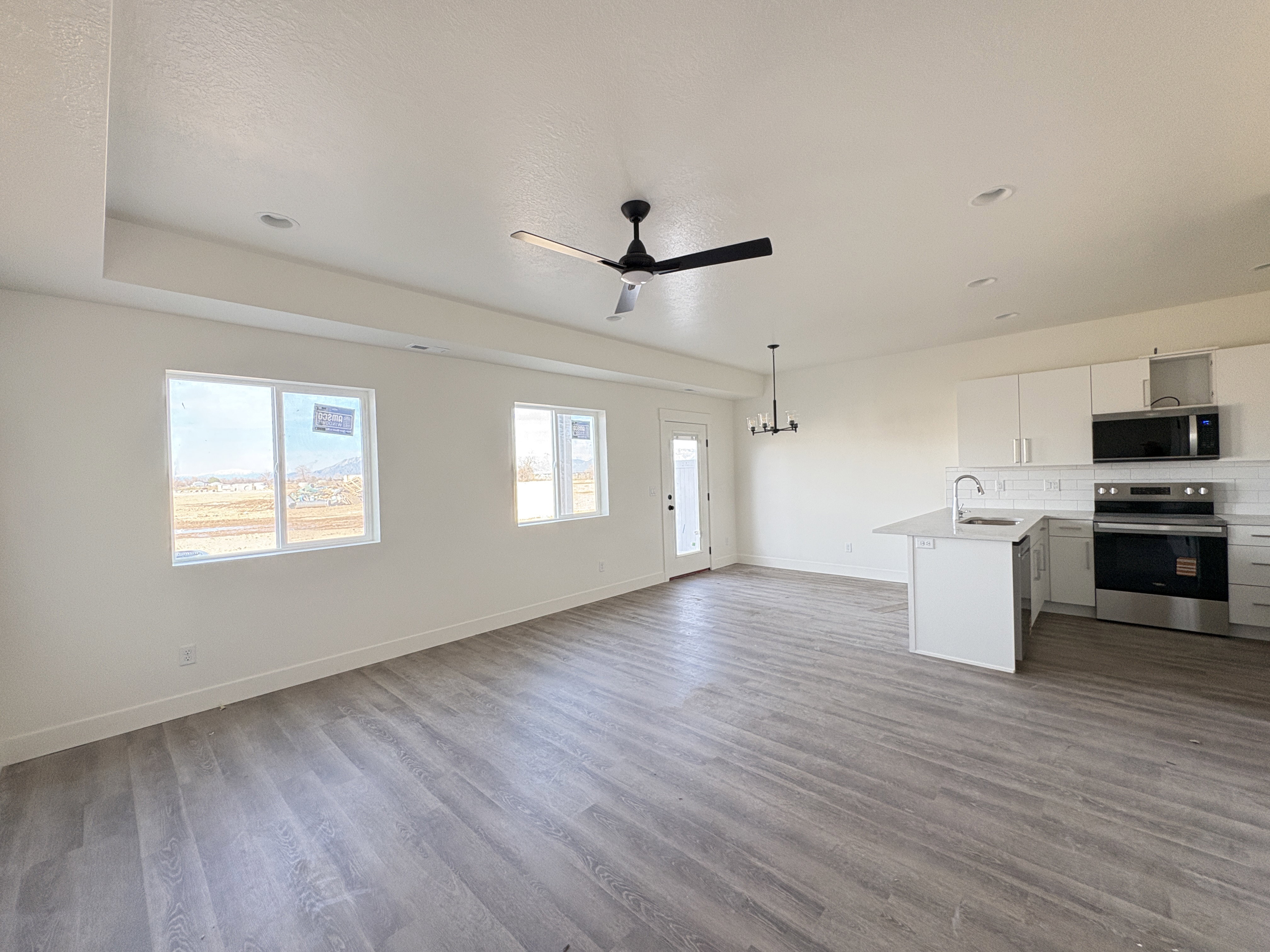 Unfurnished living room with light wood-style floors, ceiling fan, and a chandelier