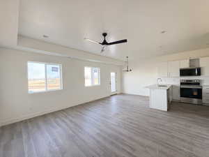 Unfurnished living room with light wood-style floors, ceiling fan, and a chandelier