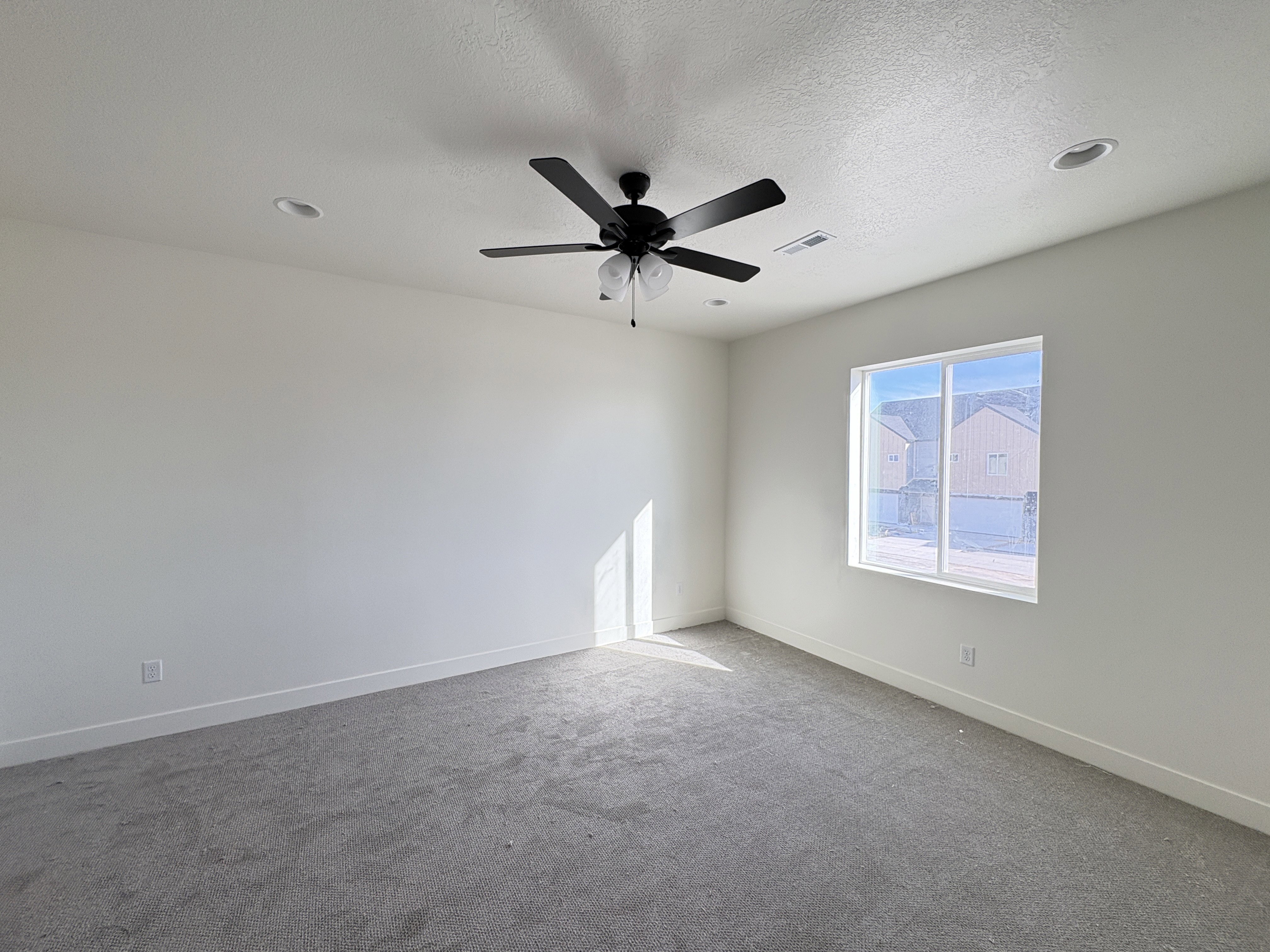Carpeted spare room with a textured ceiling and a ceiling fan