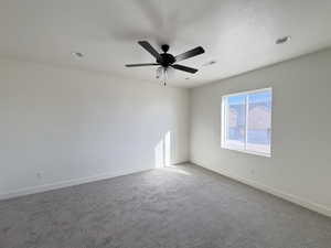 Carpeted spare room with a textured ceiling and a ceiling fan