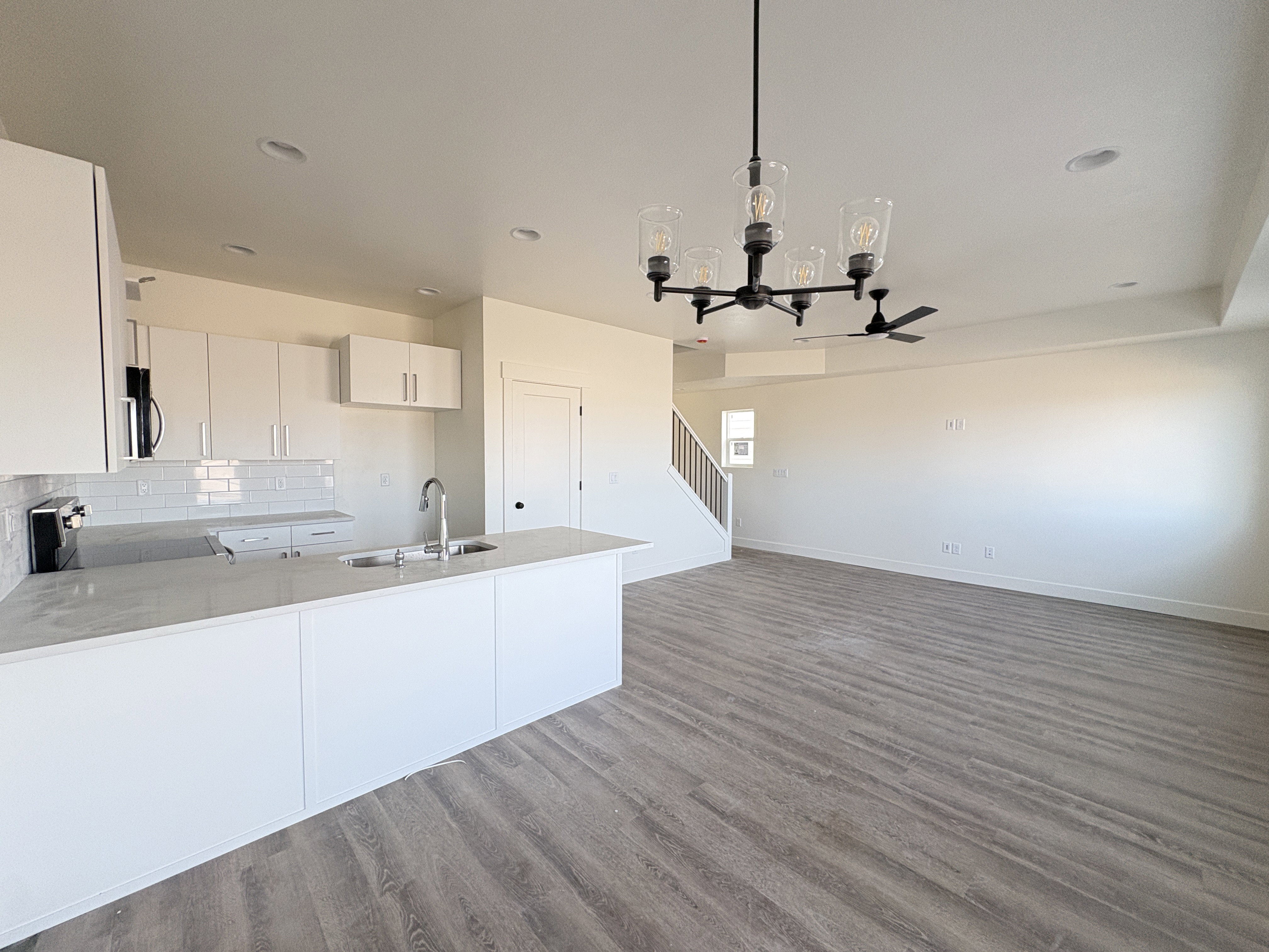Kitchen with suspended lighting, white cabinets, a peninsula, dark wood-style flooring, and stainless steel appliances