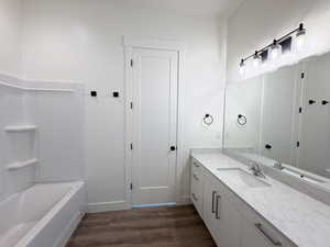 Bathroom with vanity, dark wood finished floors, and tub / shower combination