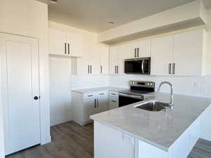 Kitchen with stainless steel appliances, a peninsula, dark wood-type flooring, and backsplash