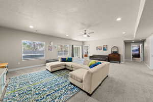 Living room with light carpet, ceiling fan, a textured ceiling, and recessed lighting