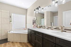 Bathroom with double vanity, a shower stall, a bath, and light wood finished floors