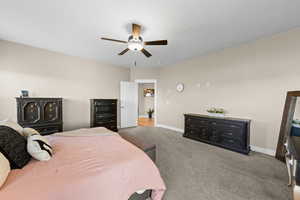 Carpeted bedroom featuring baseboards and ceiling fan
