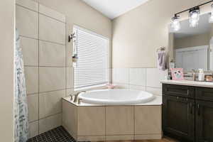 Bathroom with a bath, a tile shower, vanity, and tile walls