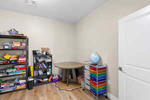 Playroom with light wood-style flooring and a textured ceiling