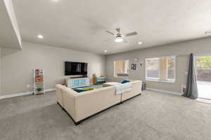 Living area featuring a ceiling fan, light carpet, recessed lighting, and a textured ceiling