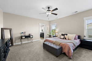 Bedroom with light colored carpet, ceiling fan, and ensuite bath