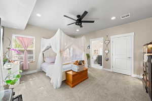Bedroom with light colored carpet, a ceiling fan, and ensuite bathroom