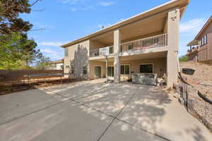 Back of property with a fenced backyard, a hot tub, a trampoline, a balcony, and stucco siding
