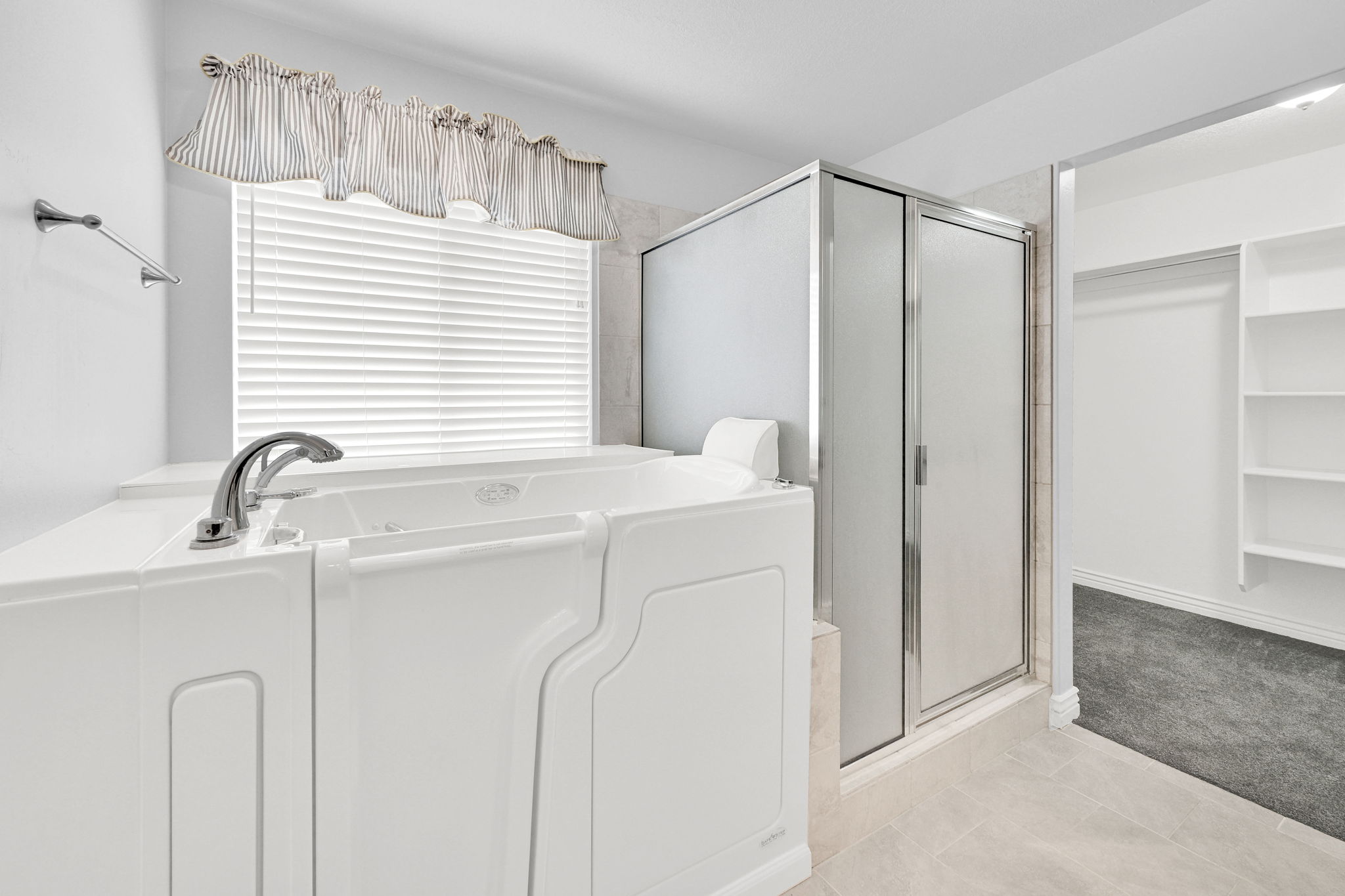 Full bath featuring a spacious closet, a shower stall, light colored carpet, and a garden tub