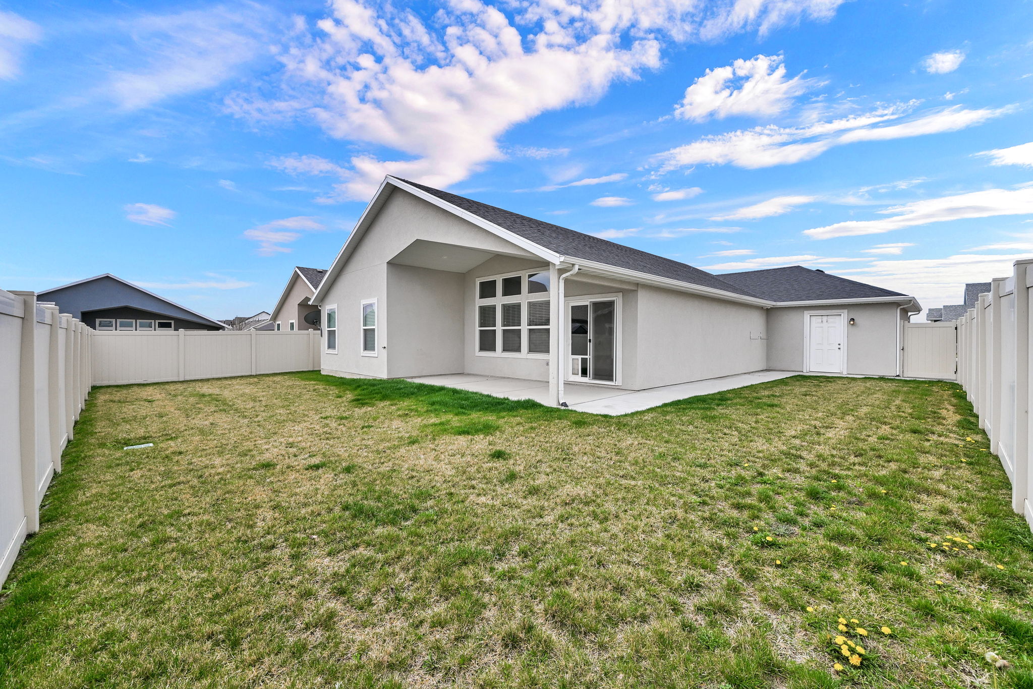 Back of property with stucco siding, a fenced backyard, a patio area, and roof with shingles