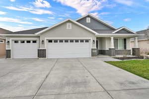 View of front facade with stucco siding, a garage, driveway, brick siding, and covered porch