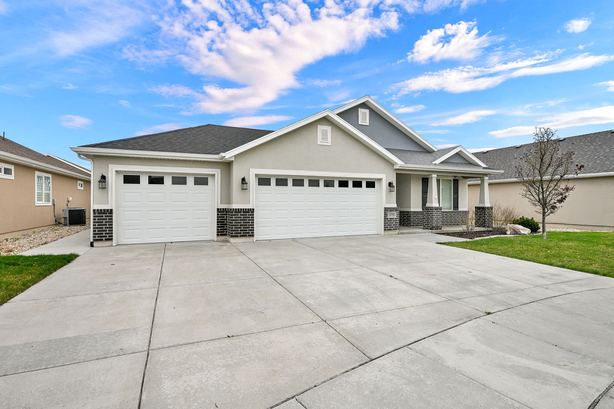 View of front facade with a garage, stucco siding, brick siding, covered porch, and driveway