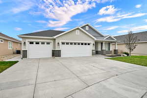 View of front facade with a garage, stucco siding, brick siding, covered porch, and driveway