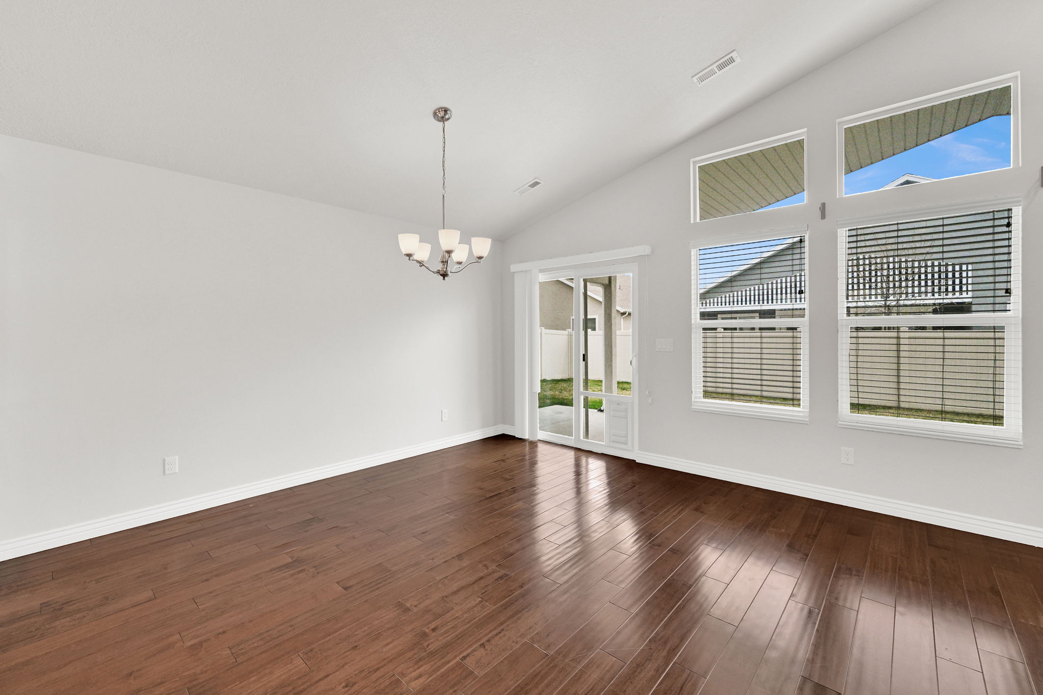 Spare room featuring hanging lights, dark wood finished floors, and lofted ceiling