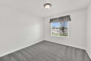 Spare room with dark colored carpet and baseboards