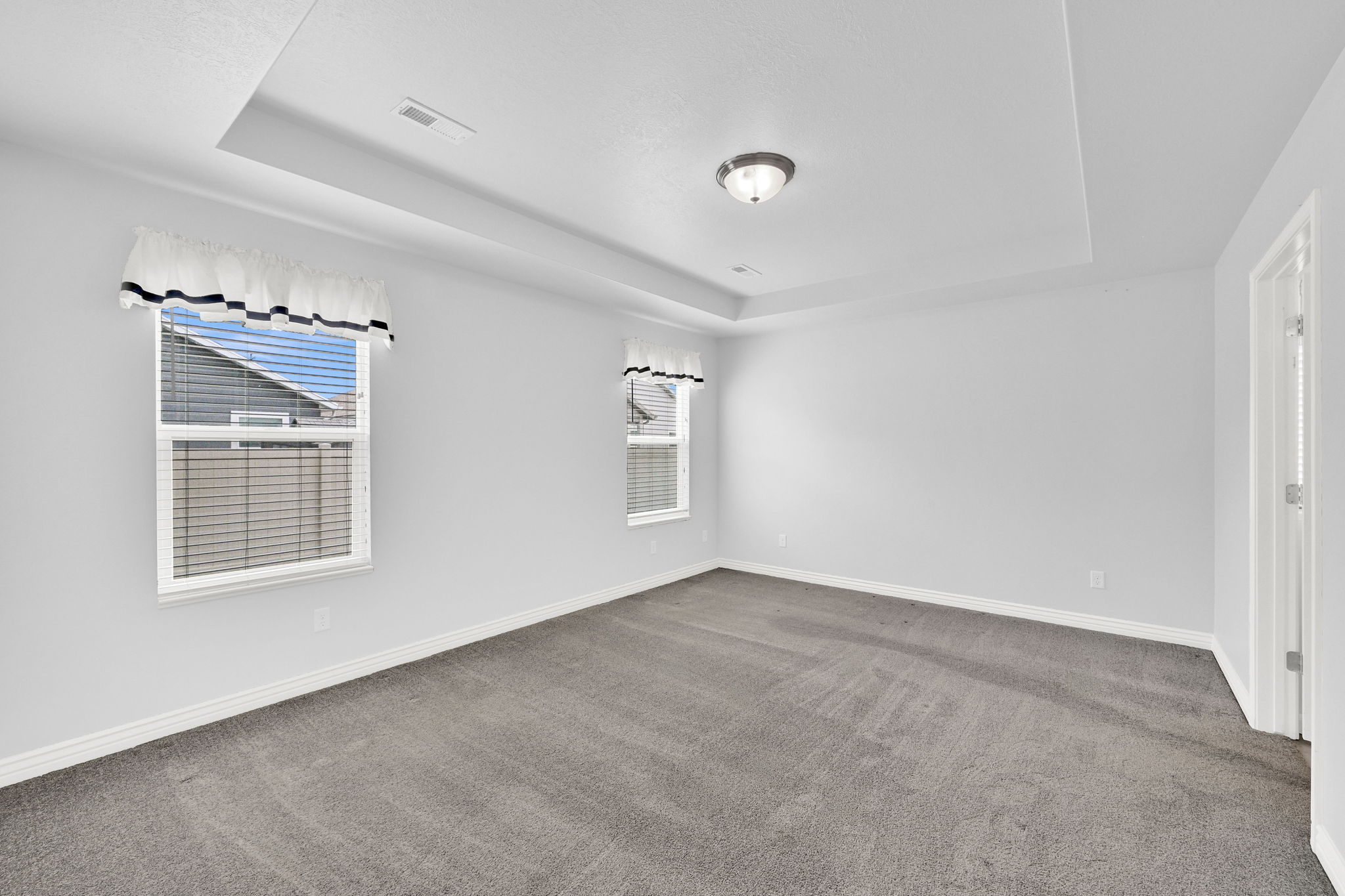 Unfurnished room featuring a tray ceiling and dark carpet