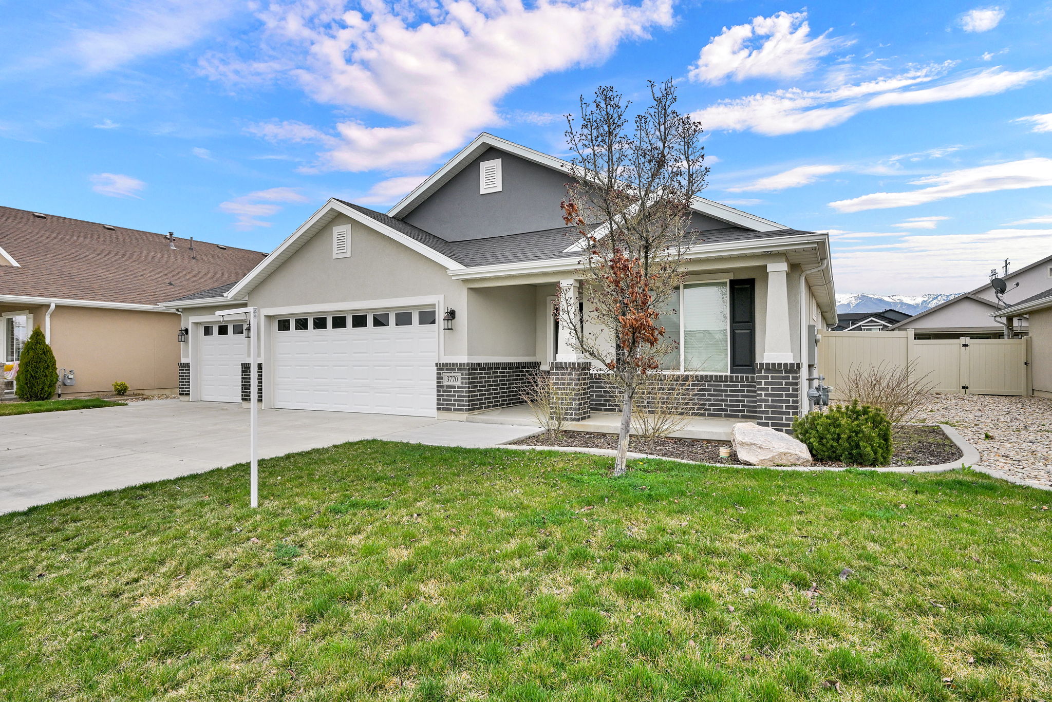 View of front of home with an attached garage, brick siding, stucco siding, concrete driveway, and covered porch