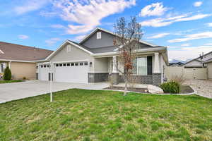 View of front of home with an attached garage, brick siding, stucco siding, concrete driveway, and covered porch