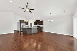 Kitchen with hanging lights, an island with sink, stainless steel appliances, a ceiling fan, and dark wood-style floors