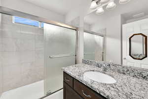 Bathroom featuring vanity and combined bath / shower with glass door