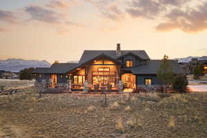 Back of house at dusk with board and batten siding, a chimney, a patio, and a shingled roof