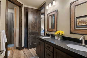 Bathroom featuring double vanity, a stall shower, and light wood-style flooring