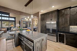 Kitchen featuring open floor plan, beverage cooler, high end refrigerator, light wood-style floors, and a kitchen island