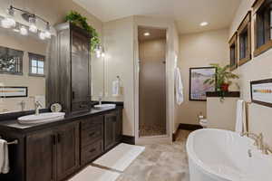 Bathroom featuring a soaking tub, double vanity, a stall shower, recessed lighting, and light tile patterned floors