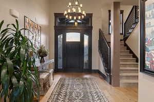 Entryway featuring light wood-style flooring, hanging lights, and a high ceiling